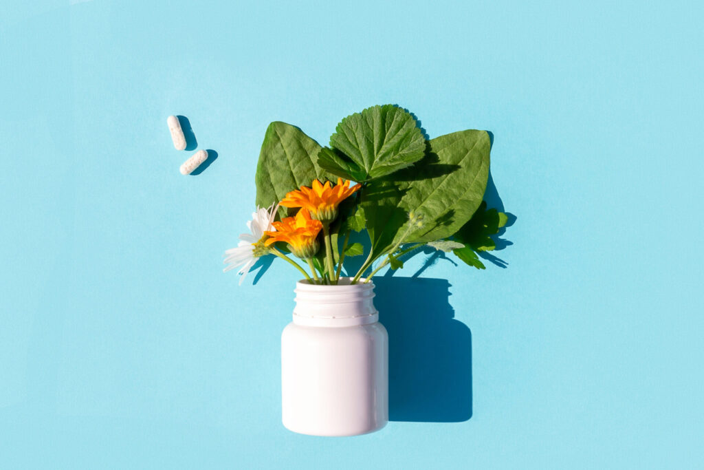 White pills and of bottle with herbal on blue background. Homeopathy, naturopathy, nutraceuticals and healthcare concept. Top view Flat lay